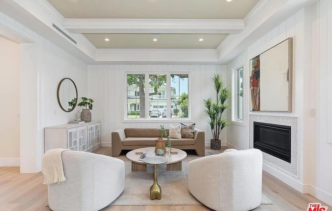 Bright living room with fresh white walls, beamed ceiling, and a tiled fireplace