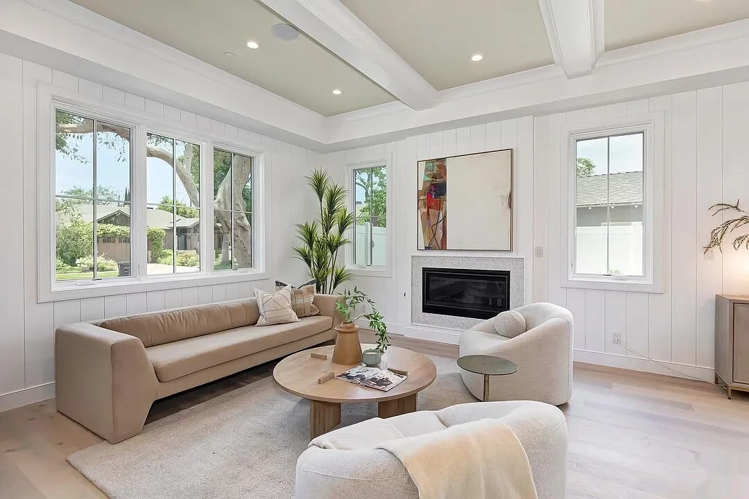 Living room with painted beamed ceiling, white shiplap walls and a fireplace