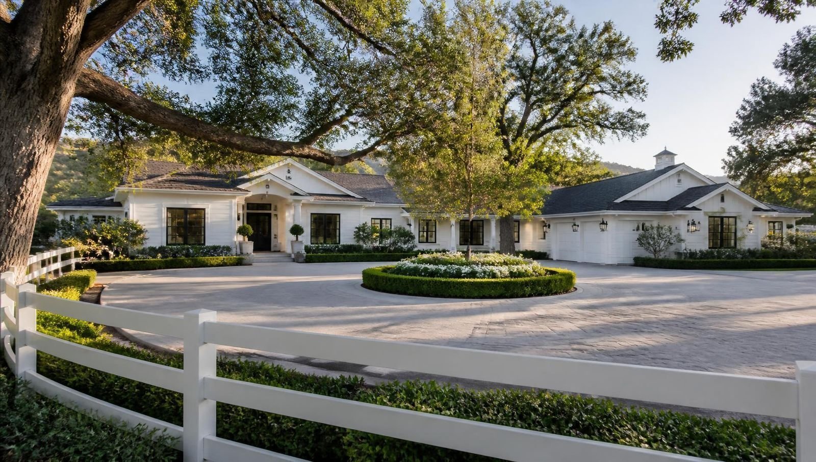 Freshly painted white ranch estate in Hidden Hills with white rail fencing and oak trees