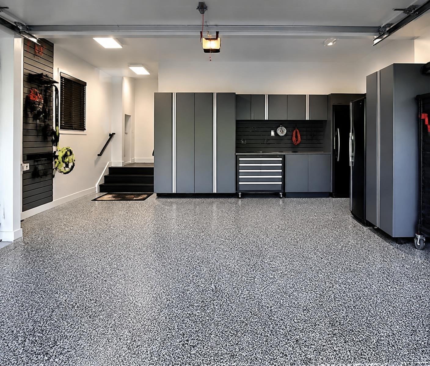 Finished home garage with a gray flake epoxy floor and dark storage cabinets