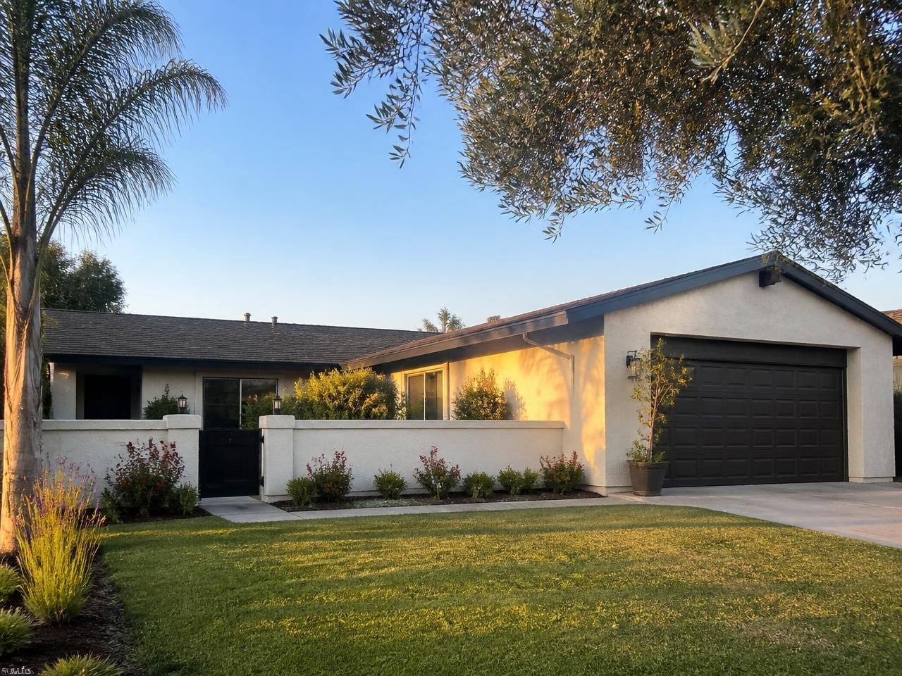 Single story ranch home with newly recoated beige stucco and a garden wall