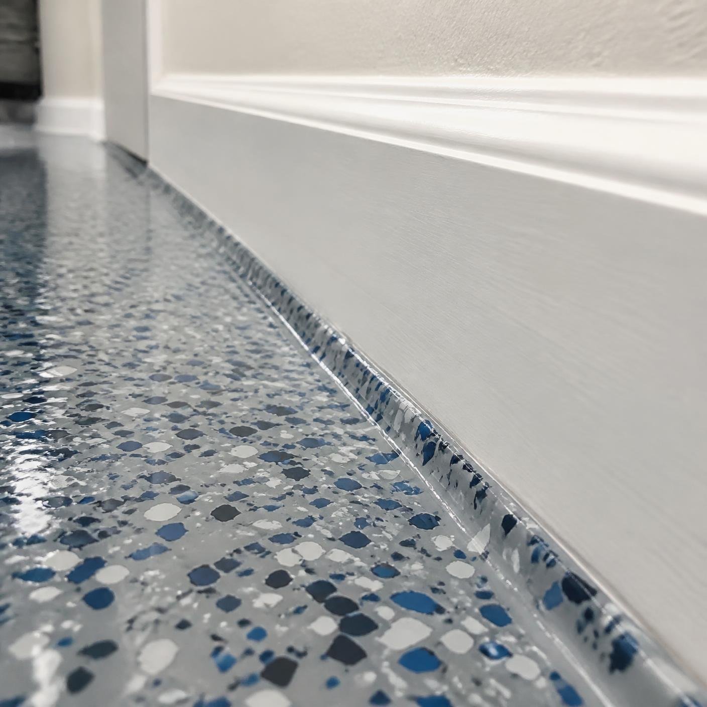 Close up of a flake epoxy floor meeting a clean white baseboard