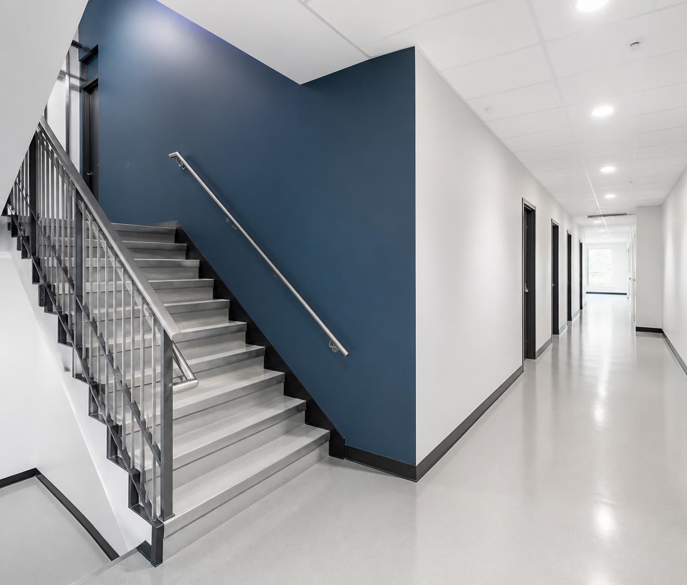 Office corridor and stairwell with white walls and a deep blue accent wall