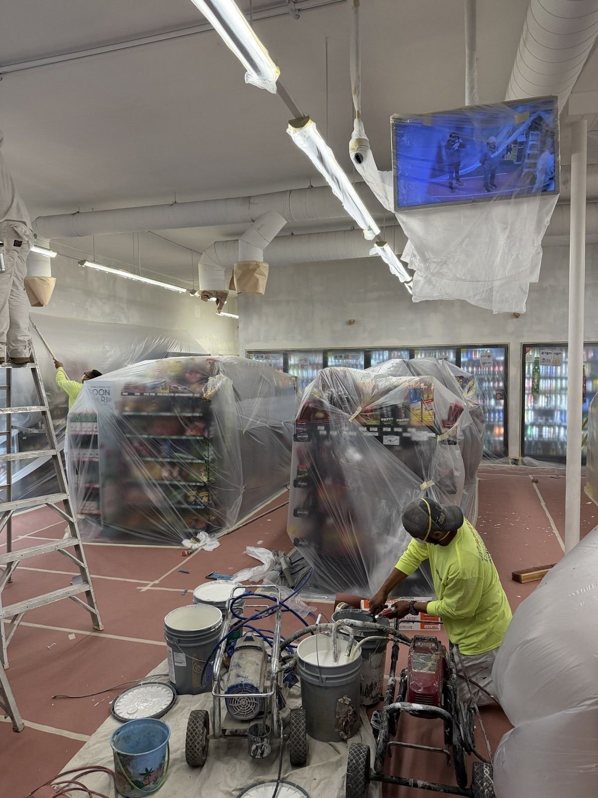 Commercial space with taped trim and covered fixtures during a repaint