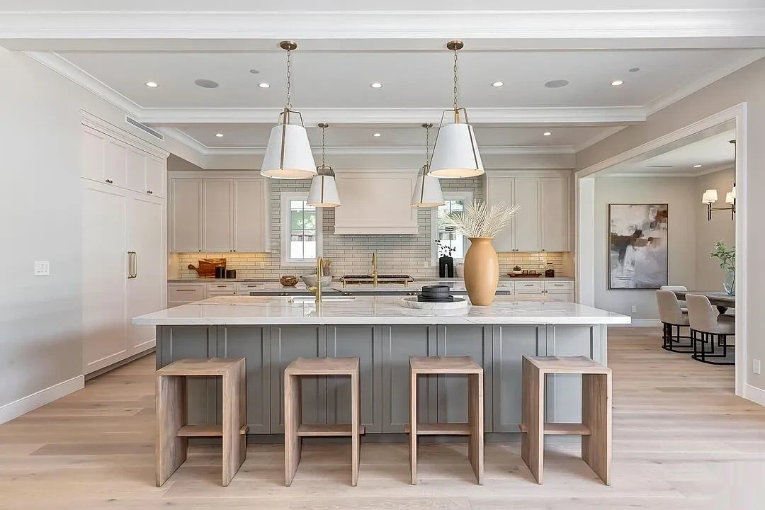Kitchen with painted cabinets, gray island and warm white walls