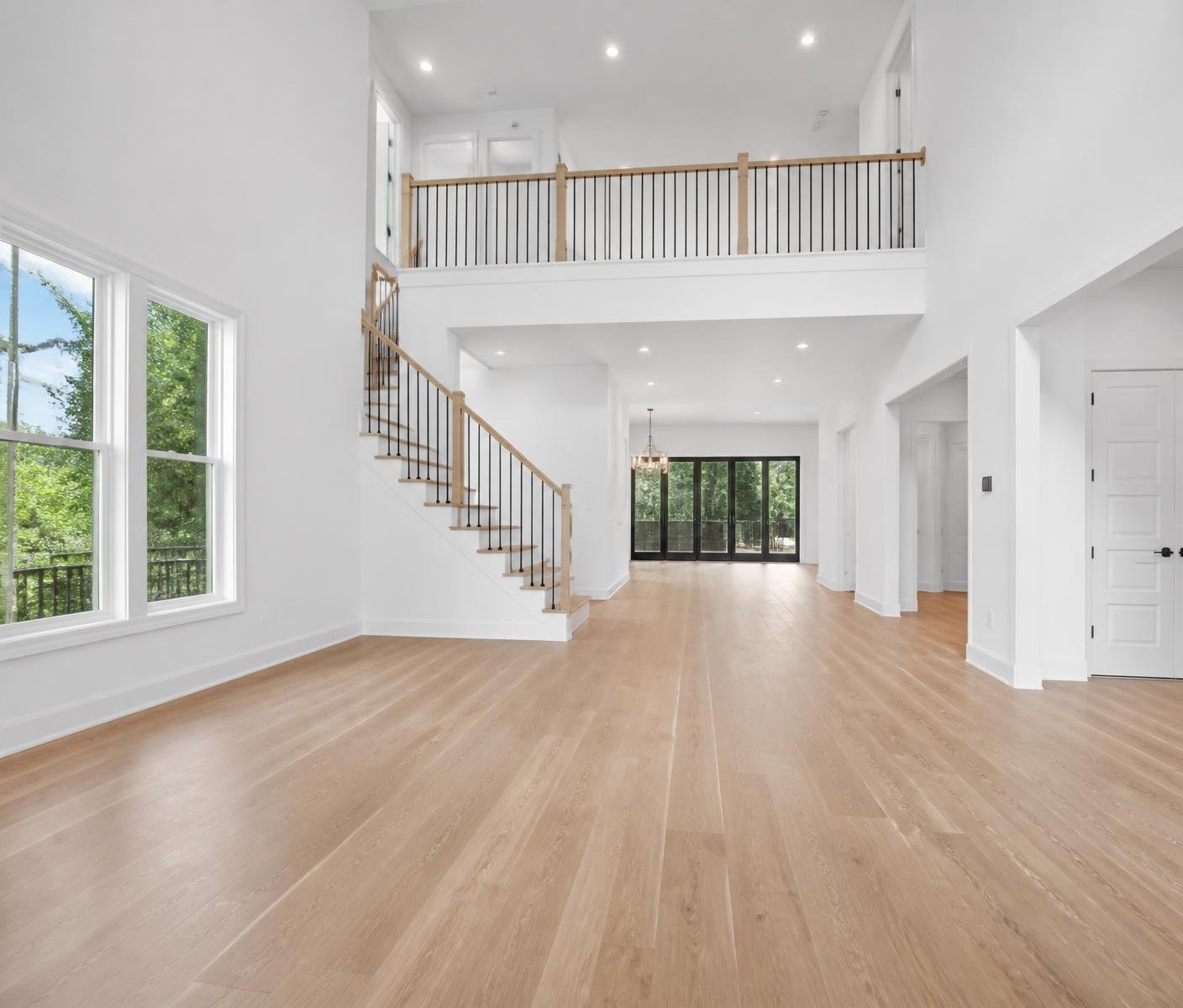 Empty new construction great room with freshly painted white walls, tall ceilings and new oak floors