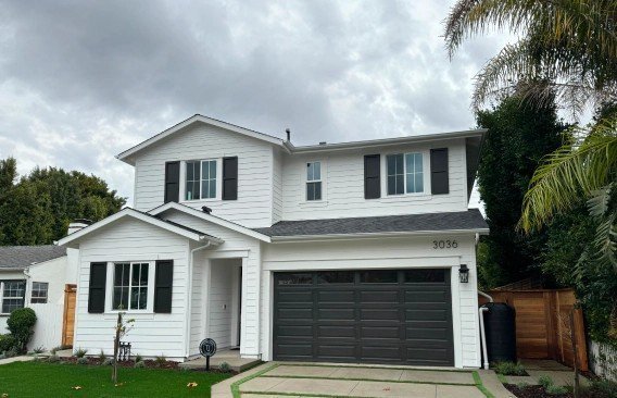 Large repainted two story home with crisp white trim on a hillside lot