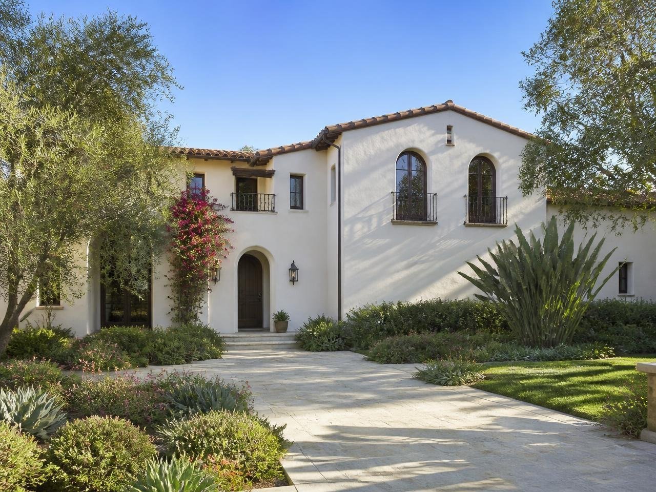 Spanish revival home with cream stucco walls, arched windows and wrought iron balconies