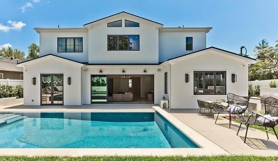 White two story modern farmhouse with black window trim and a pool after an exterior repaint