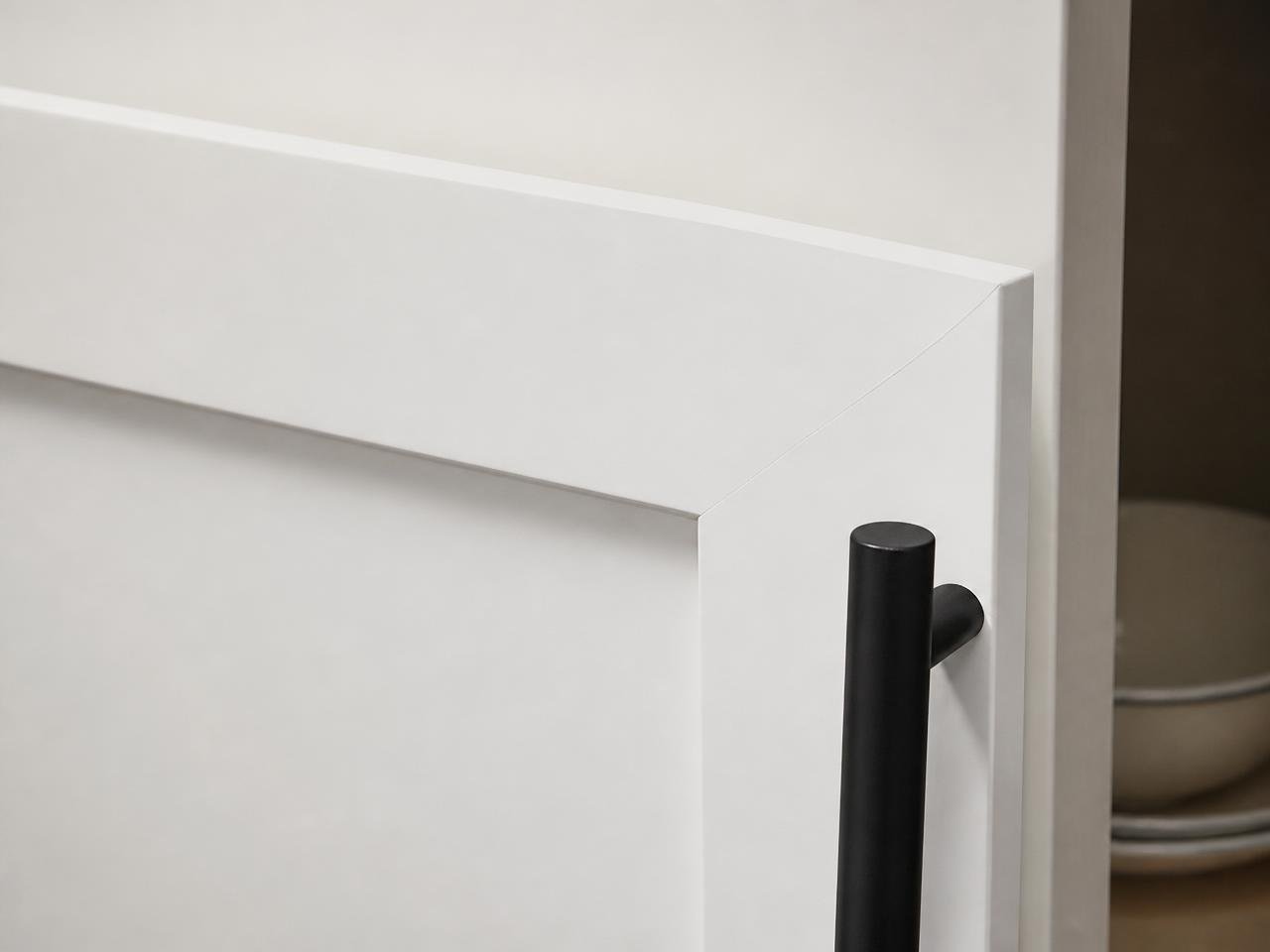 Close up of a smooth sprayed white shaker cabinet door with black hardware